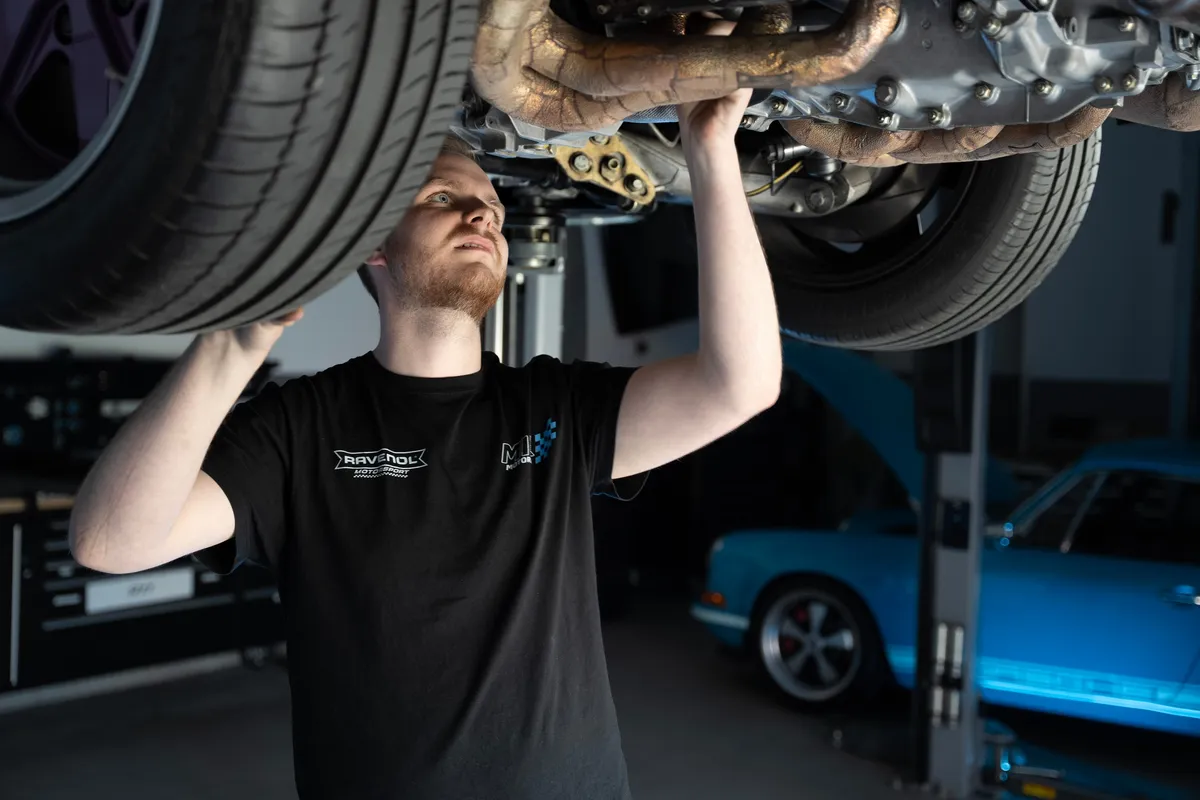 Mechaniker von MIK Motoren arbeitet an der Unterseite eines Fahrzeugs auf der Hebebühne